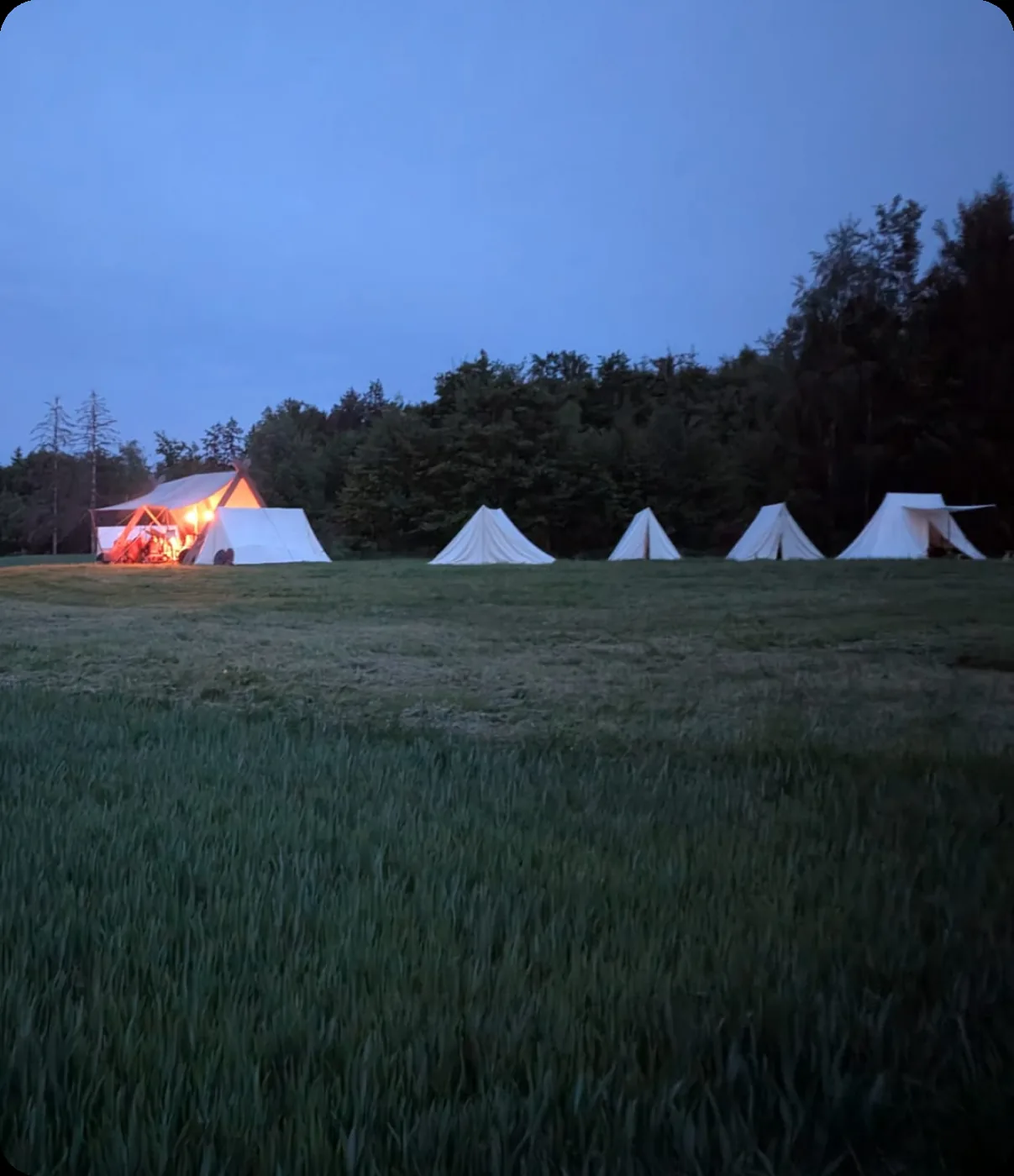 Die Zelte des Lagers in der Abenddämmerung, eines von innen beleuchtet